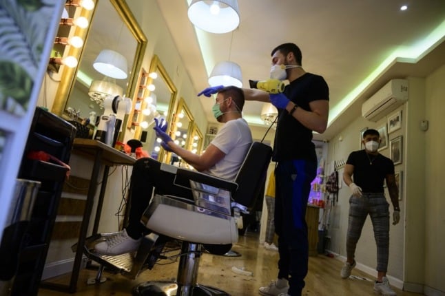 A hairdresser blowdries a client's hair after reopening his barber shop in Madrid, on May 4, 2020, for the first time since the beginning of a national lockdown to prevent the spread of the COVID-19 disease. - Masks became mandatory on public transport today as Spain took its first tentative steps towards a commercial reopening with small businesses accepting customers by appointment and restaurants prepping food for takeaway. Spain's population of nearly 47 million people have been confined to their homes for more than 50 days as the country sought to curb the spread of the deadly virus which has so far claimed 25,428 lives. (Photo by PIERRE-PHILIPPE MARCOU / AFP)