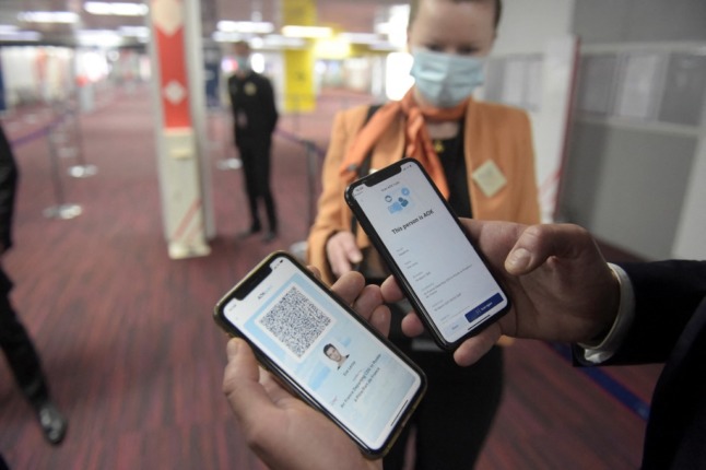A man displays smartphones showing the AOK pass app at the arrivals area of Roissy-Charles de Gaulle airport 