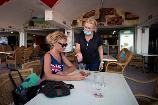 A waitress talks to a tourist at a restaurant on a beach in Magaluf on the Island of Mallorca on July 27, 2020. - Tour operator TUI has cancelled all British holidays to mainland Spain from today until August 9, after the UK government's decision to require travellers returning from the country to quarantine. (Photo by JAIME REINA / AFP)