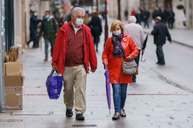 People wearing face masks walk in Burgos, northern Spain, 