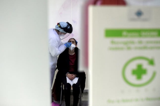 A pharmacist conducts an antigen rapid test for COVID-19 at a pharmacy in Madrid. (Photo by OSCAR DEL POZO / AFP)