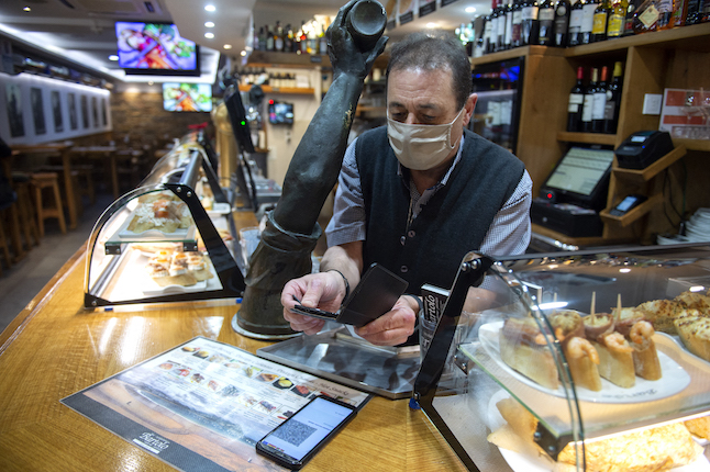 A waiter checks Covid pass at a bar in Spain