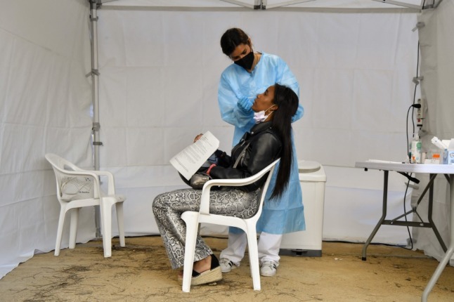 A health worker collects a swab sample for a COVID-19 test from a woman.
